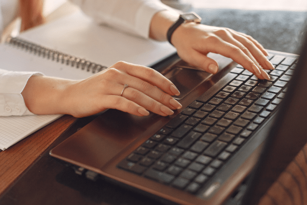 Vrouwenhanden die typen op een laptop